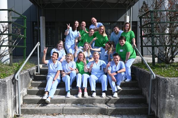 Na fotografiji pred vhodom v Center za dializo sedijo in stojijo zaposlene medicinske sestre in administratorka.