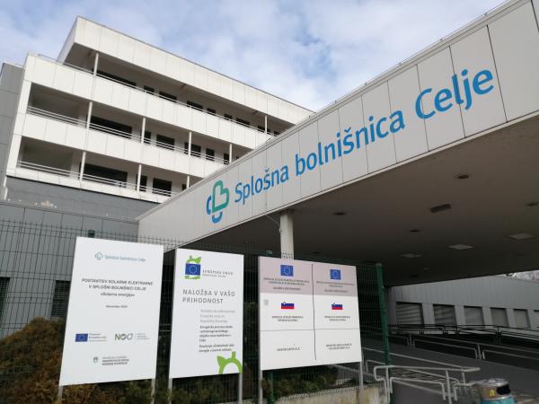 Fotografija vhoda 1 z označevalnimi tablami, iz katerih je razviden naslov projekta: Postavitev solarne elektrarne v Splošni bolnišnici Celje 